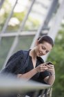 Бізнес-леді в сірому піджаку з волоссям, використовуючи смартфон у місті . — стокове фото