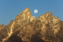 Gamma montuosa frastagliata nel parco nazionale del Grand Teton con luna piena in cielo . — Foto stock