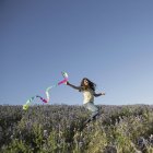 Elementary idade menina correndo com papel streamer fluttering no ar . — Fotografia de Stock