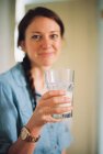 Mulher com trança segurando vidro de água limpa . — Fotografia de Stock