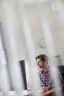 View through office partition of man working at desk. — Stock Photo
