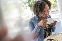 Mulher segurando e cheirando xícara de café no café . — Fotografia de Stock