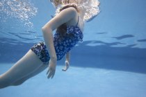 Pre-adolescent girl swimming underwater in pool. — Stock Photo
