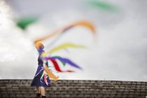 Female artist moving line of flags during performance at street stairs. — Stock Photo