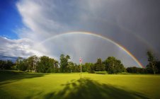 Doppelter Regenbogen im Himmel über grünem Golfplatz. — Stockfoto