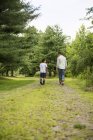Dos hermanos caminando por el camino del campo en el bosque, vista trasera . - foto de stock
