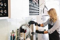 Woman in protective gloves cleaning equipment at hair salon. — Stock Photo