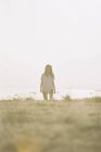 Жінка з довгим волоссям у білій сорочці, що стоїть на трав'яному схилі . — стокове фото