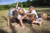 Famille avec trois enfants jouant dans le parc . — Photo de stock