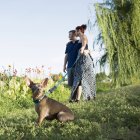 Coppia passeggiando nel parco con cane chihuahua su piombo blu . — Foto stock
