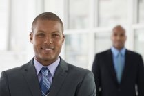 Two men in suits standing in office and looking in camera. — Stock Photo