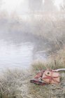Creel de pesca e cobertor na margem do rio com varas de pesca . — Fotografia de Stock