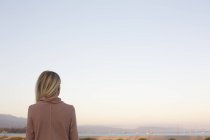 Femme blonde debout à l'océan, vue arrière . — Photo de stock
