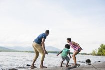 Família com filho brincando na margem do lago na floresta . — Fotografia de Stock