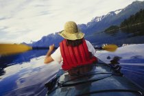 Rear view of woman kayaking on calm water of Muir Inlet in Glacier Bay National Park, USA. — Stock Photo