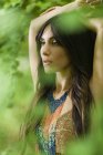 Porträt einer Frau mit langen braunen Haaren mit erhobenen Armen im Freien im Wald. — Stockfoto