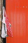 Vividamente pintado puerta naranja y manchado bolsas de tela colgando de clavo . - foto de stock