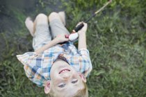 Overhead view of elementary age boy fishing outdoors and looking up. — Stock Photo