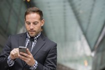 Man with short red hair and beard in suit using smartphone in street. — Stock Photo