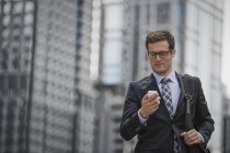 Бізнесмен у костюмі та краватці перевіряє смартфон на міській вулиці . — стокове фото