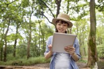 Mujer joven usando tableta digital en bosque soleado
. - foto de stock