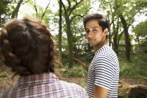 Mixed race man looking over shoulder with young woman in forest. — Stock Photo