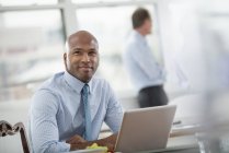 Mid adult man sitting at desk and using laptop in office workplace. — Stock Photo