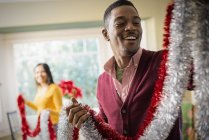 Young couple decorating house with tinsel at Christmas. — Stock Photo
