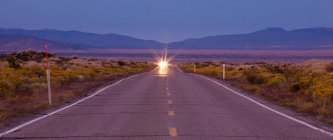 Luces de coche en la carretera a través de la pradera en Bodie, California, EE.UU. - foto de stock