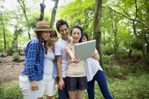 Group of Asian friends taking selfie with digital tablet in forest. — Stock Photo