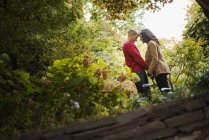 Mid adult man and woman holding hands in city park under trees. — Stock Photo