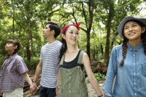 Group of friends walking and holding hands in forest. — Stock Photo