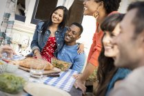 Cheerful couple with friends gathering around dinning table. — Stock Photo