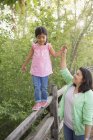 Elementary age girl in pink shirt walking along fence and holding hands with mother. — Stock Photo