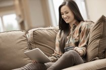 Женщина сидит на диване и покупки в Интернете с цифровой планшет и кредитная карта . — стоковое фото