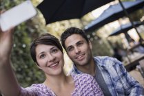 Couple sitting at city cafe and taking selfie with smartphone. — Stock Photo