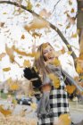 Ridere ragazza adolescente gettando foglie autunnali in aria nel parco . — Foto stock