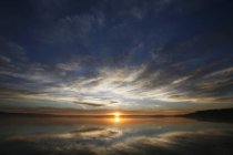 Sonne am Horizont über der Wasseroberfläche des Sees im Morgengrauen in Kanada. — Stockfoto