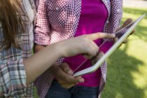 Vista cortada de duas meninas tocando tela de tablet digital com as mãos . — Fotografia de Stock