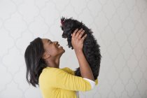Side view of teenage girl holding small black pet dog. — Stock Photo
