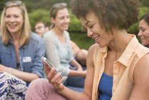 Jovem com afro usando telefone no grupo de amigos ao ar livre . — Fotografia de Stock