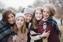 Five teenage girls in warm shawls and woolly hats posing outdoors. — Stock Photo