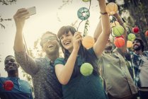 Cheerful woman and man taking selfie at party with paper lanterns outdoors. — Stock Photo