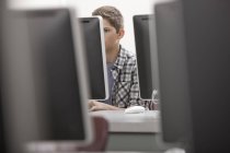 Pré-adolescent travaillant dans un laboratoire informatique avec des rangées de moniteurs d'ordinateur . — Photo de stock