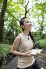 Young woman holding book and looking up in forest. — Stock Photo