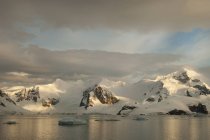 Atardecer y aguas tranquilas planas de la orilla del paisaje de montaña en la Antártida . - foto de stock