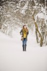Mulher adulta média andando na neve na floresta . — Fotografia de Stock