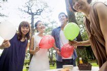 Group of friends holding balloons at outdoor party in forest. — Stock Photo