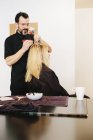 Peluquero masculino usando papel de aluminio mientras se tiñe el cabello rubio de cliente femenino . - foto de stock