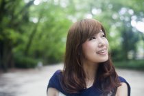 Retrato de jovem mulher japonesa olhando para longe no parque . — Fotografia de Stock
